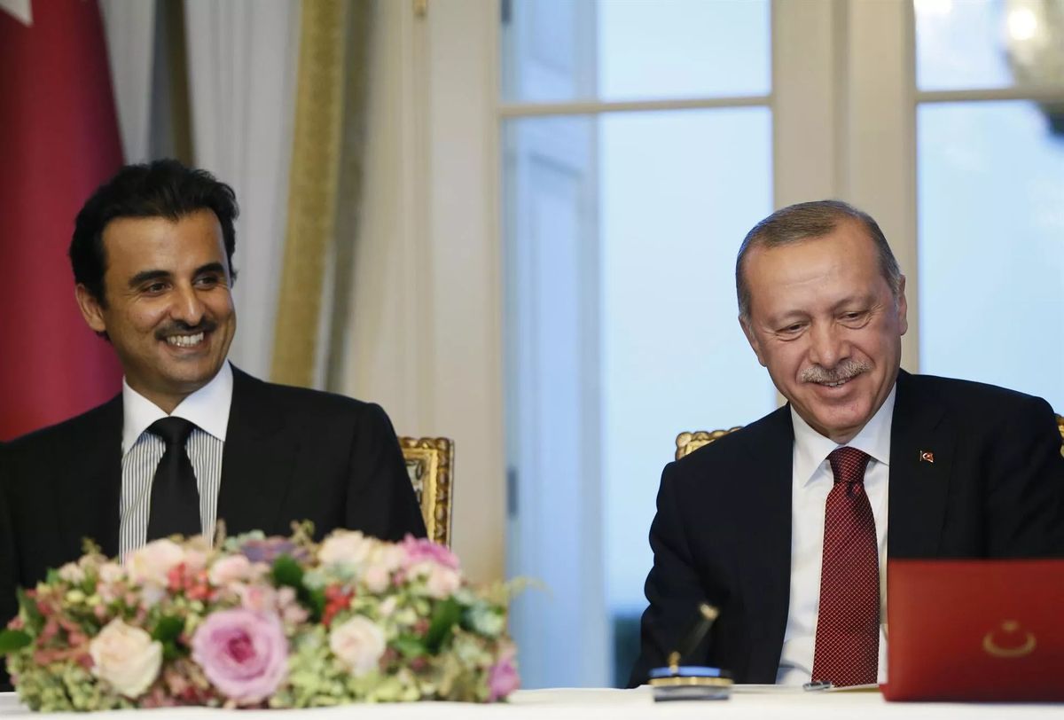 Katar Devleti Emiri Şeyh Temim bin Hamad Al Sani ve Cumhurbaşkanı Erdoğan masada gülümsüyor.