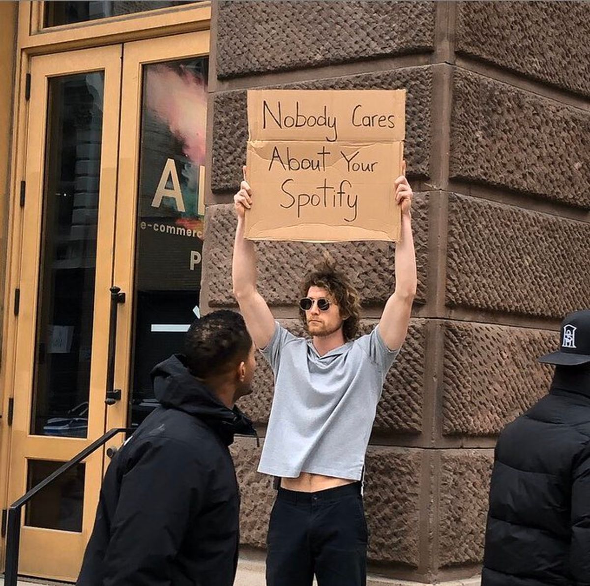 dudewithsign kullanıcı adlı Instagram fenomeni, elinde "hiç kimse sizin Spotify'ınızı umursamıyor" pankartı tutuyor.