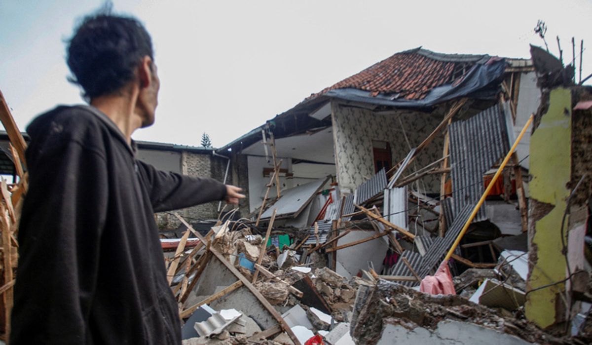 Endonezya'da meydana gelen depremin ardından bir kişi yıkılan ebi gösteriyor