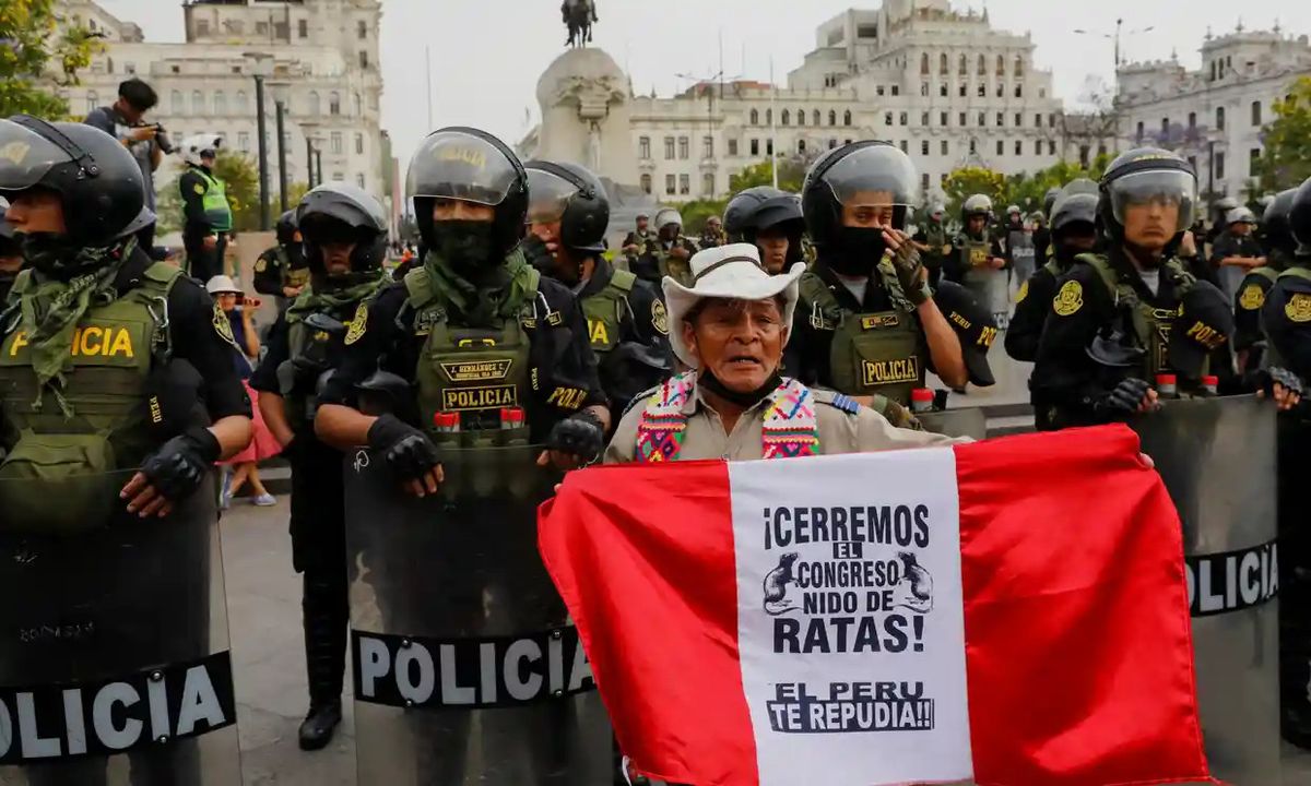 Peru'nun Lima kentinde Salı günü Perulu lider Pedro Castillo'nun devrilmesinin ardından düzenlenen protestoya katılan bir gösterici, üzerinde 'Kongre fare yuvasını kapatalım' yazan bir bayrak tutuyor. 